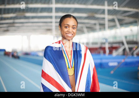 Young female athlete wrapped in UK flag with gold medal Stock Photo