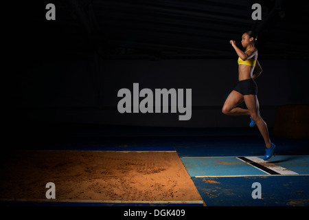 Young female athlete doing long jump Stock Photo