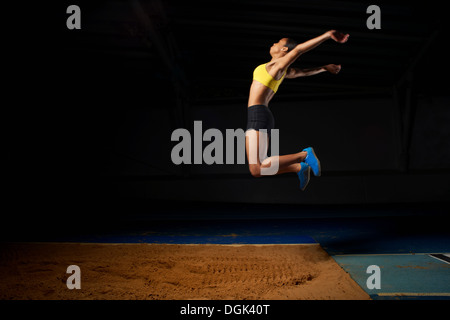 Young female athlete doing long jump Stock Photo