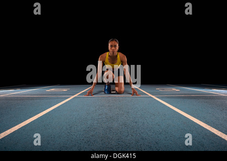 Young female athlete on starting blocks Stock Photo