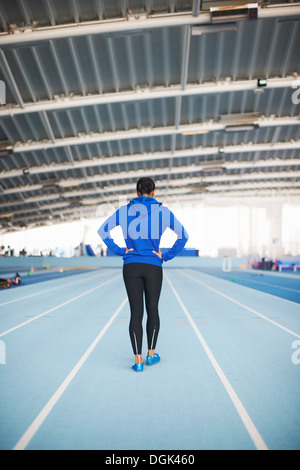 Young female athlete with hands on hips, rear view Stock Photo