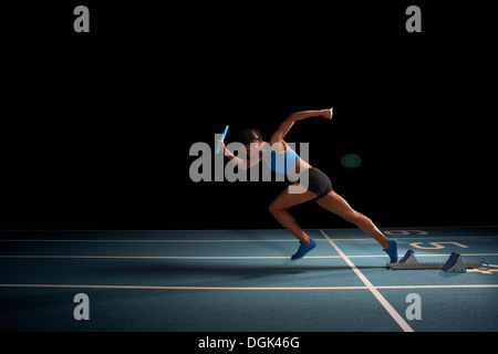 Young female athlete in relay race Stock Photo