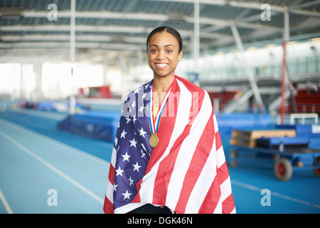 Young female athlete wrapped in US flag with gold medal Stock Photo