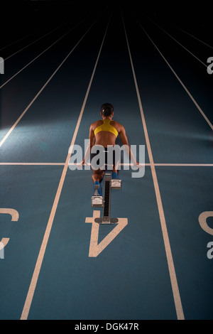 Young female athlete on starting blocks, high angle Stock Photo