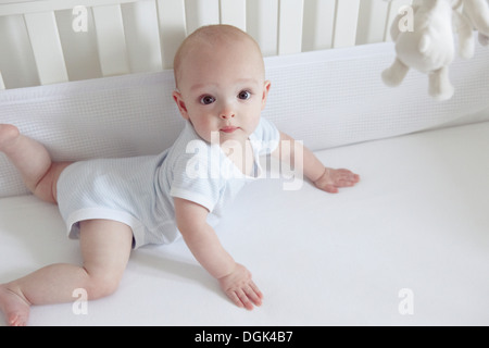 Baby boy crawling in cot Stock Photo