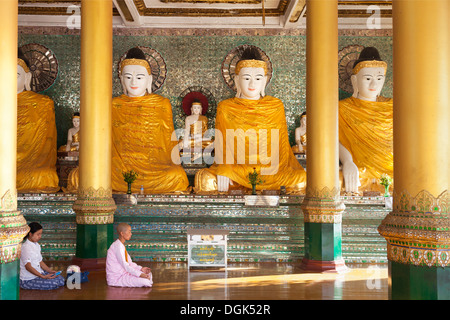 A nun and woman praying before Buddhas in Shwedagon Pagoda in Yangon Myanmar. Stock Photo