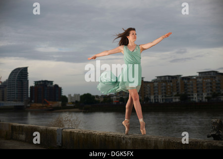 Ballet dancer standing on tiptoe on wall Stock Photo