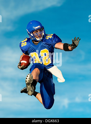 American footballer with ball against blue sky Stock Photo