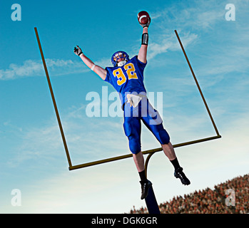 American footballer jumping to catch ball in front of goal Stock Photo