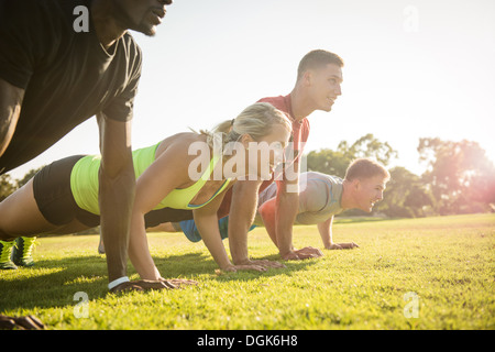 Group of young adults doing push-ups in field Stock Photo