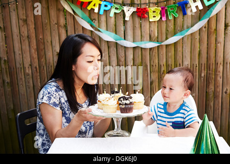 Mother blowing out candles on baby boy's birthday cakes Stock Photo