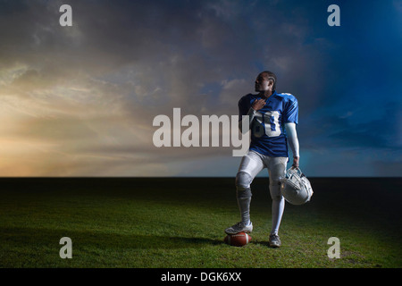 Portrait of American football player resting foot on ball Stock Photo