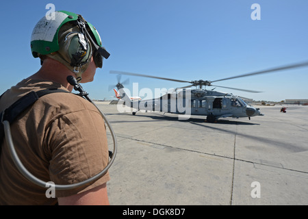 Sailor assigned to Helicopter Sea Combat Squadron (HSC) 26 maintains a flight line perimeter around an MH-60S Seahawk helicopter. HSC-26 Det. 1 is a Forward-Deployed Naval Force (FDNF) asset attached to Commander, Task Force 53 to provide combat logistics Stock Photo