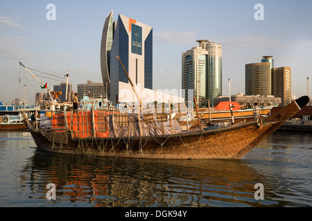 A boat trawls along Dubai Creek at dawn. Stock Photo