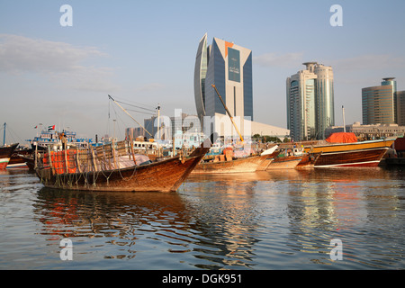 A boat trawls along Dubai Creek at dawn. Stock Photo