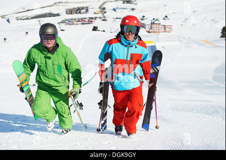 Skiers carrying equipment up hill Stock Photo