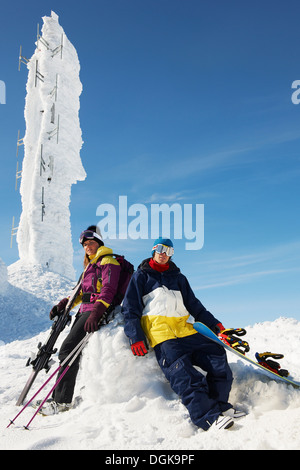 Snowboarder and skier at the top of mountain with equipment, in front of ice sculpture Stock Photo