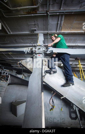 SOUTH CHINA SEA (Oct. 21, 2013) Aviation Machinist's Mate 2nd Class Bryan Myers, from Mathews, N.C., performs maintenance on the tail rotor of an MH-60S Sea Hawk helicopter from the Golden Falcons of Helicopter Sea Combat Squadron (HSC) 12 in the hangar b Stock Photo