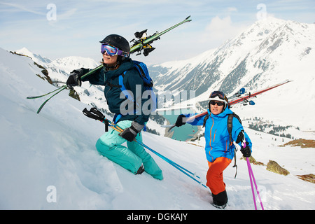 Skiers carrying equipment to top of mountain Stock Photo