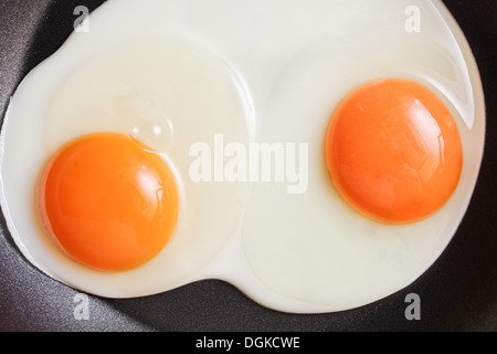 Two fresh eggs being fried in a non-stick pan Stock Photo
