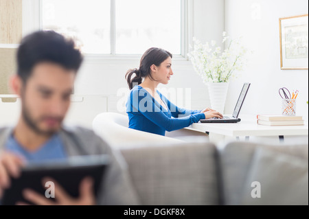 Woman using laptop and man using digital tablet at home Stock Photo