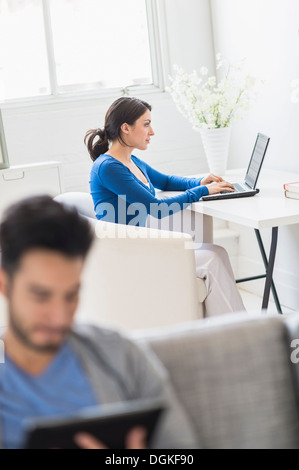 Woman using laptop and man using digital tablet at home Stock Photo