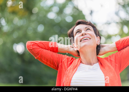 Happy mature woman raising hands in park Stock Photo