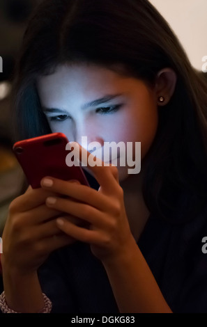 Girl (12-13) texting on mobile phone at night Stock Photo