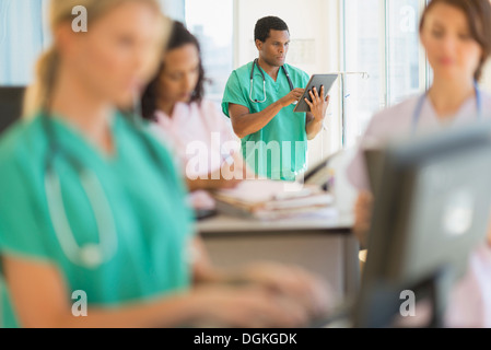 Doctors and nurses working at desks in hospital Stock Photo
