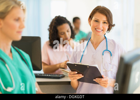 Doctors and nurses working at desks in hospital Stock Photo