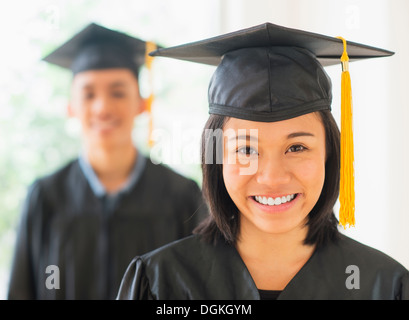 Portrait of young woman and young man wearing graduation gown Stock Photo