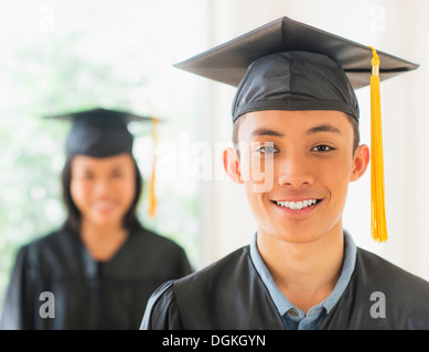 Portrait of young woman and young man wearing graduation gown Stock Photo