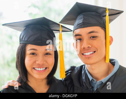 Portrait of young woman and young man wearing graduation gown Stock Photo