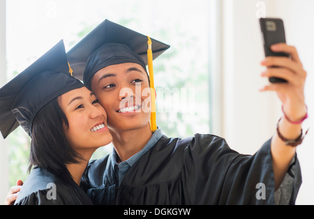 Portrait of young woman and young man wearing graduation gown Stock Photo