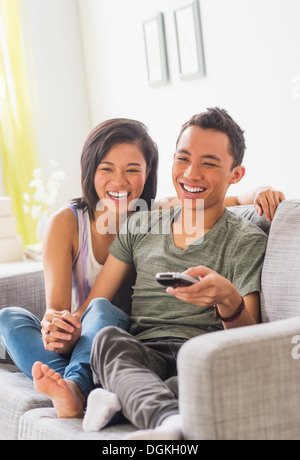 Young woman and young man sitting on sofa Stock Photo