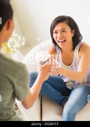 Young man giving cupcake with candle to woman Stock Photo