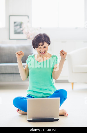 Young woman cheering in front of laptop Stock Photo