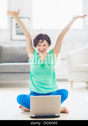 Young woman cheering in front of laptop Stock Photo