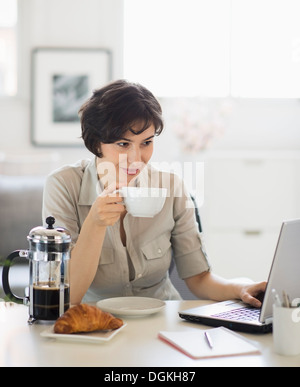 Portrait of woman having coffee and using laptop Stock Photo