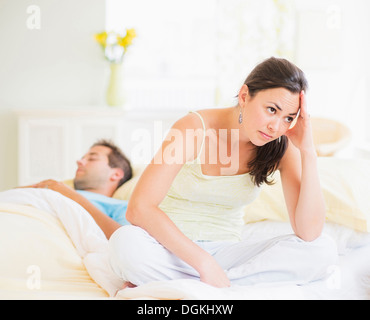 Sad woman in bedroom, man sleeping Stock Photo
