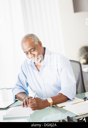 Portrait of senior man writing in office Stock Photo