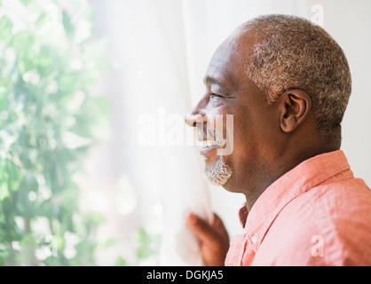 Portrait of smiling man looking through window Stock Photo