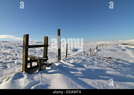 A stile across a fence high in the deeply snow covered Pennine Hills. Stock Photo