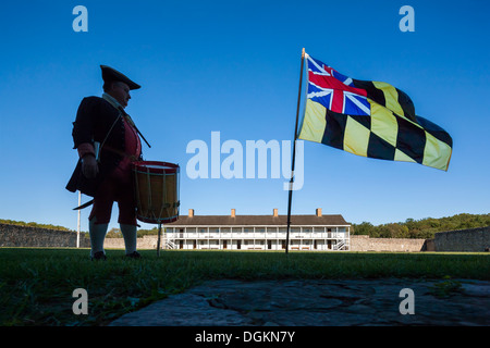 Historic daily life in Fort Frederick Maryland volunteer drummer with colonial era Maryland flag and East barracks. Stock Photo