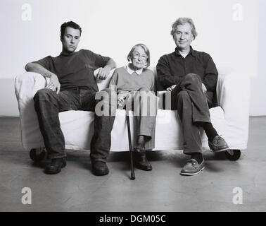 Three generations, a grandmother, her son and her grandson sitting on a sofa Stock Photo