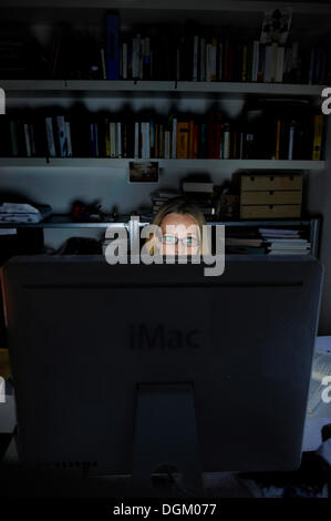 Young woman working on a computer at night Stock Photo