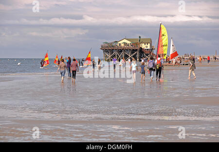 People walking across the mudflats in front of a building on stilts, St. Peter-Ording, Wadden Sea, North Sea, Schleswig-Holstein Stock Photo