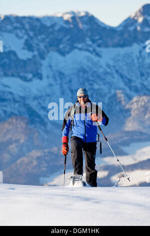 Man snowshoeing, snowshoe tour in Berchtesgadener Land, Unterberg mountain and Hochthron mountain at the back Stock Photo