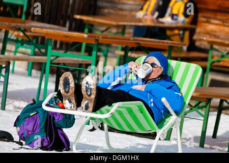 Hiker resting, drinking a mulled wine in the Hirschkaser mountain restaurant, ski region of Schwarzeck near Ramsau Stock Photo