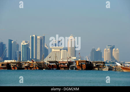 Tradition and modernity, dhow wooden cargo ships in front of the skyline of Doha, Qatar, Persian Gulf, Middle East, Asia Stock Photo